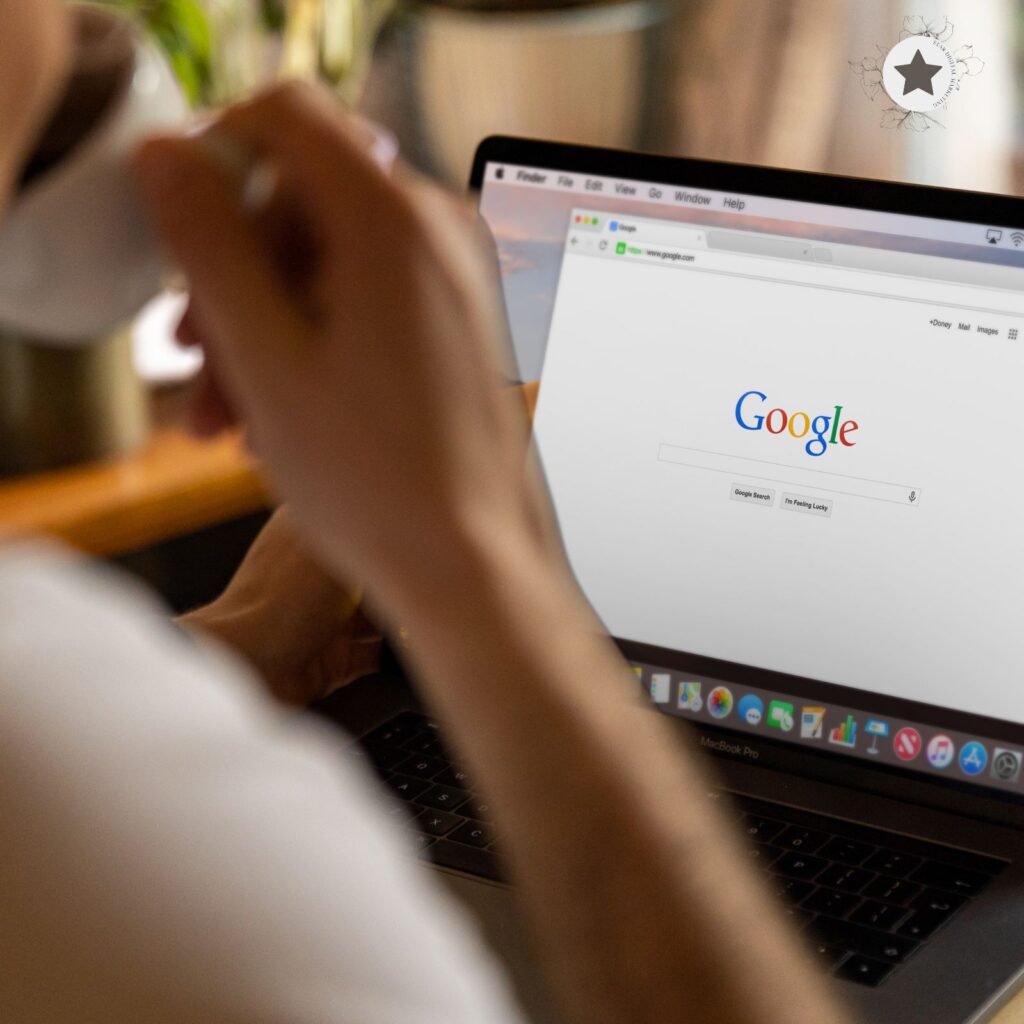 Person sipping coffee while looking at Google search page on a laptop.